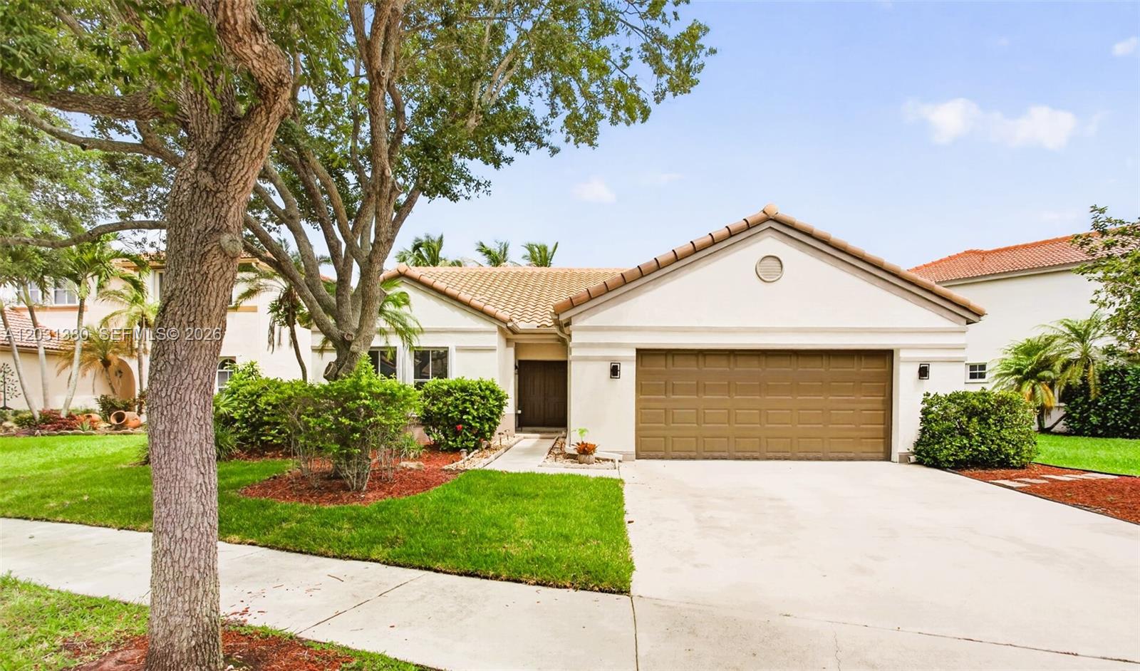 A single-story house with a beige stucco exterior, a tile roof, and a two-car garage — 370 Carrington Dr, Weston FL 33326, WESTON, FL