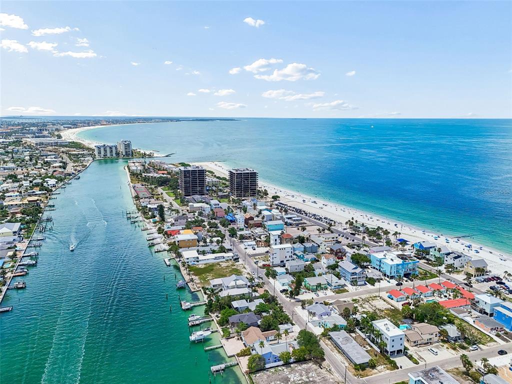 An aerial view shows a coastal town with a canal, beach, and high-rise buildings — 8125 BAYSHORE DRIVE, TREASURE ISLAND, FL