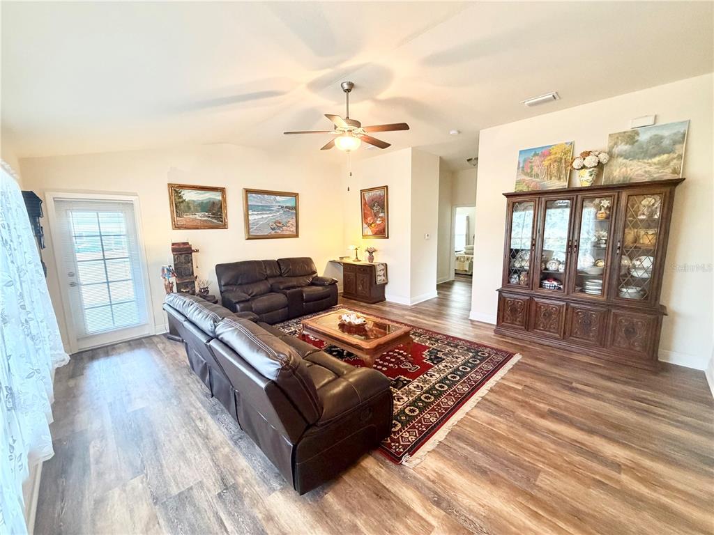 A living room features wood-look flooring, a leather sofa set, and a large wooden hutch — 8298 OSBERT AVENUE, NORTH PORT, FL