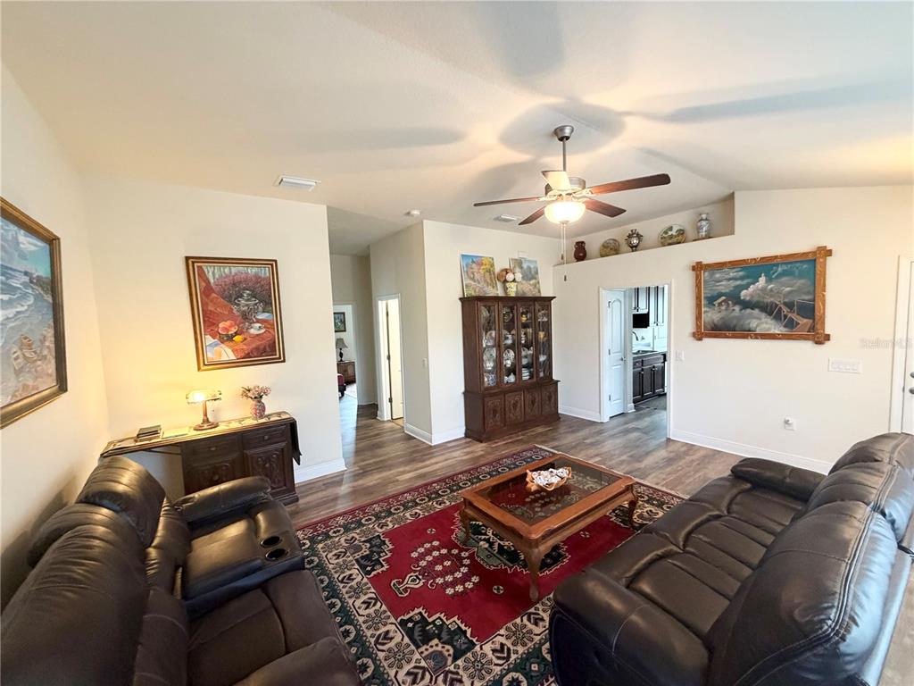A living room features dark leather sofas, a red patterned rug, and a wooden hutch — 8298 OSBERT AVENUE, NORTH PORT, FL