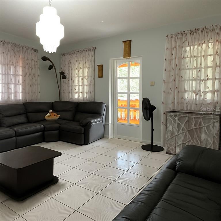 A living room features white tiled floors, black leather sectional sofas, and a glass-paned door — CANIACO RIO ABAJO STRD 123, 8201 SECTOR VENDREL, UTUADO, PR