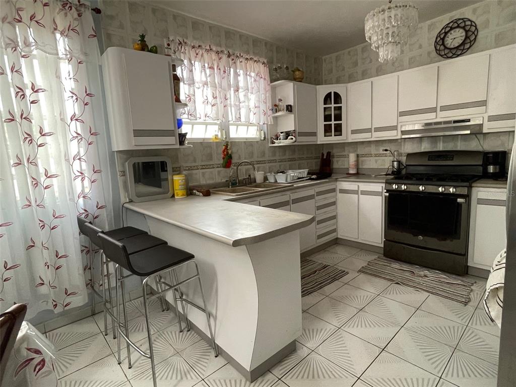 A kitchen with white cabinets, a breakfast bar, tiled floors, and a black oven — CANIACO RIO ABAJO STRD 123, 8201 SECTOR VENDREL, UTUADO, PR