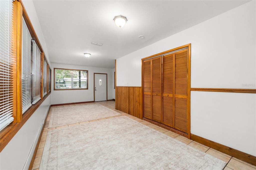 A room with tile flooring, wood-paneled wainscoting, louvered closet doors, and multiple windows — 4156 NW 10TH STREET, GAINESVILLE, FL