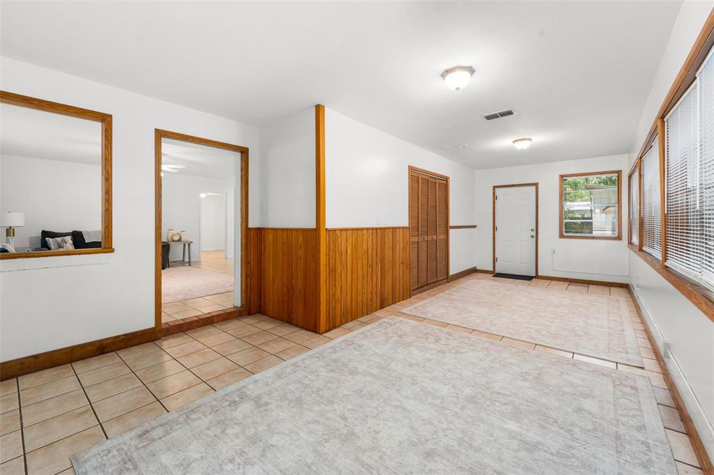 A room with tile flooring, wood paneling, a closet, and a doorway leading to another room — 4156 NW 10TH STREET, GAINESVILLE, FL