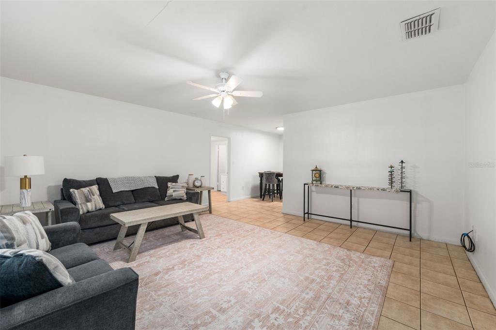 A living room features a gray sofa, a light wood coffee table, and tile flooring — 4156 NW 10TH STREET, GAINESVILLE, FL