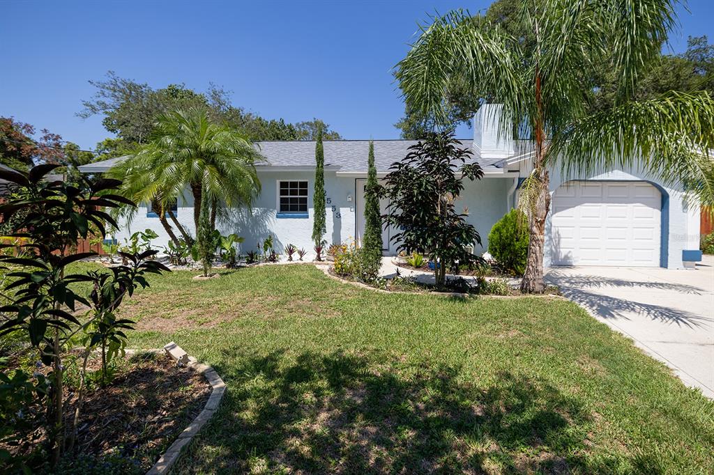 A light blue single-story house features a white garage door and a landscaped front yard — 2553 NORDMAN AVENUE, NEW SMYRNA BEACH, FL