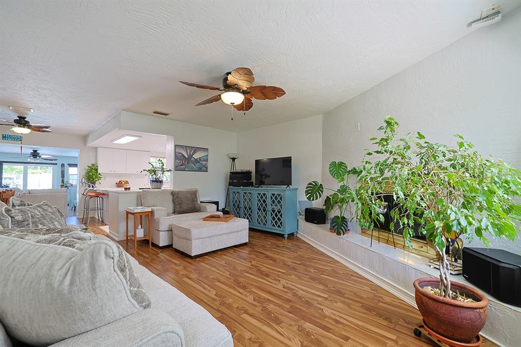 A living room with wood-look flooring, a ceiling fan, a fireplace, and a blue cabinet — 2553 NORDMAN AVENUE, NEW SMYRNA BEACH, FL
