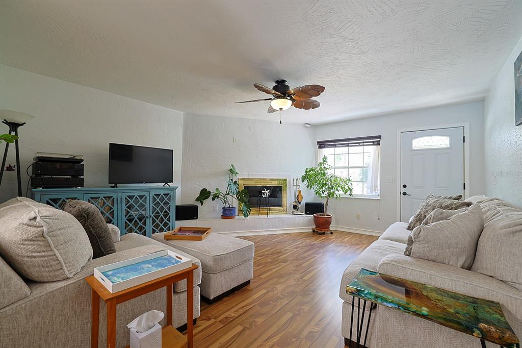 A living room features light-colored sofas, a fireplace, a ceiling fan, and wood-look flooring — 2553 NORDMAN AVENUE, NEW SMYRNA BEACH, FL