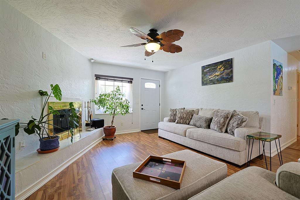 A living room features a fireplace, a beige sofa, a ceiling fan, and wood flooring — 2553 NORDMAN AVENUE, NEW SMYRNA BEACH, FL