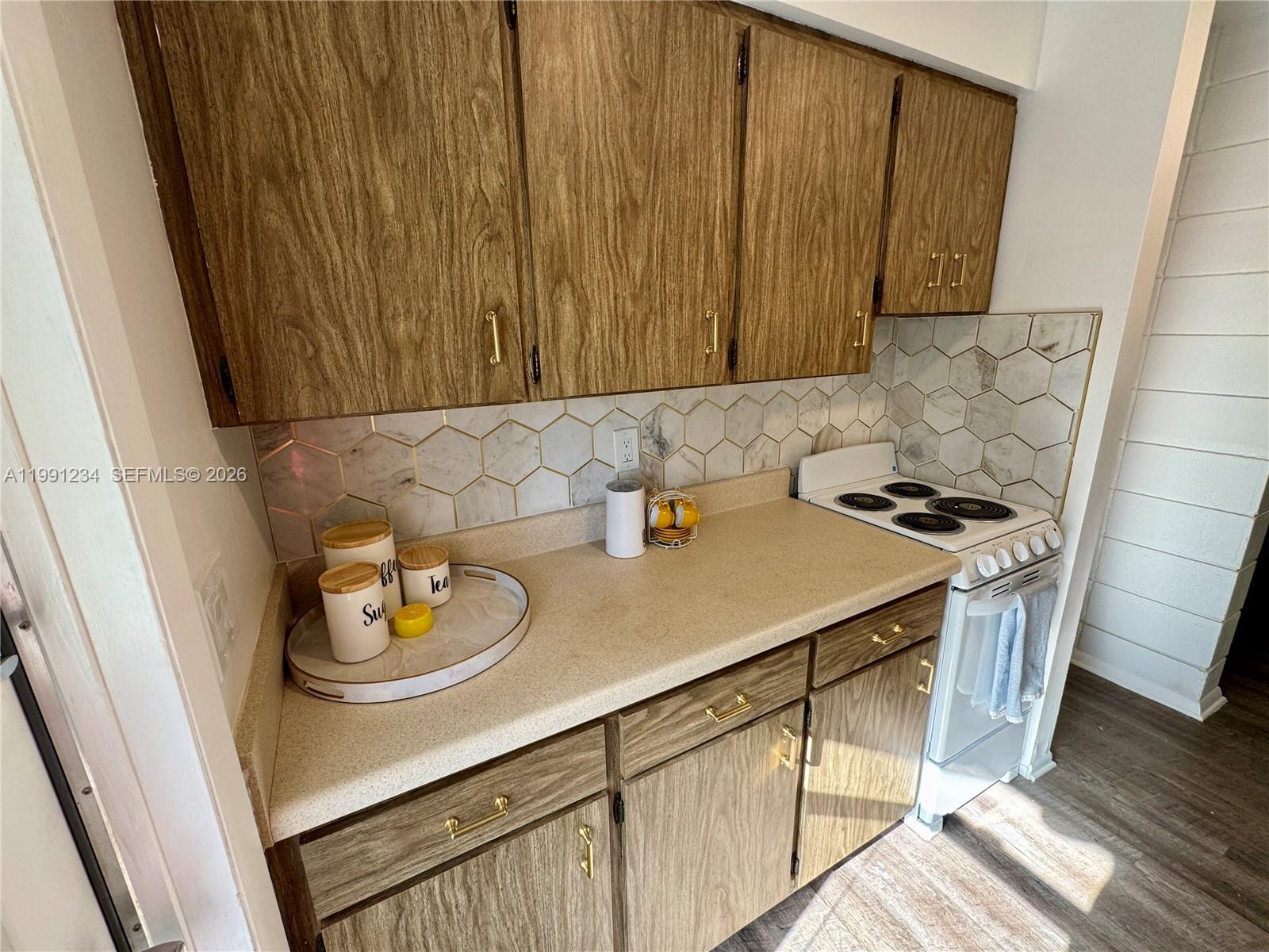 A kitchen features wood-grain cabinets, a beige countertop, and a white hexagonal tile backsplash — 5100 Rilma Ave # 0, Sarasota FL 34234, SARASOTA, FL