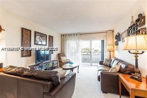 A living room features brown leather sofas, a television, and a sliding glass balcony door — 1980 S Ocean Dr # 2B, Hallandale Beach FL 33009, HALLANDALE BEACH, FL