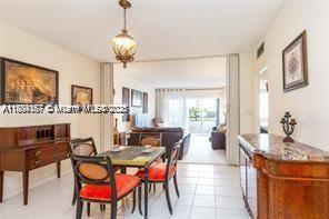 A dining area with a wooden table and chairs leads into a bright living room — 1980 S Ocean Dr # 2B, Hallandale Beach FL 33009, HALLANDALE BEACH, FL