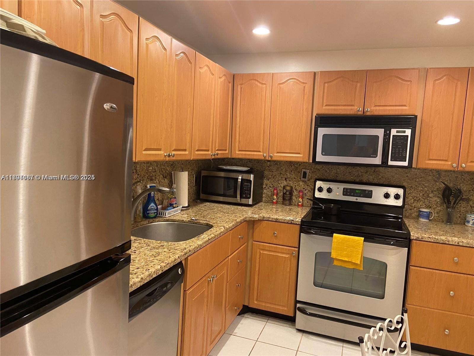 A kitchen features wood cabinets, granite countertops, and stainless steel appliances — 1980 S Ocean Dr # 2B, Hallandale Beach FL 33009, HALLANDALE BEACH, FL