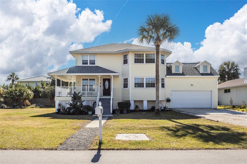 A two-story yellow house with a front porch, attached garage, and a palm tree — 44 FLAGLER DRIVE, PALM COAST, FL