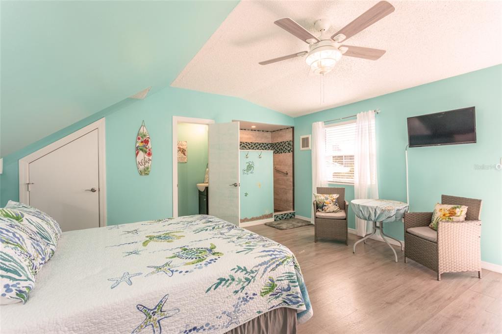 A bedroom with light blue walls, a turtle-patterned quilt, a ceiling fan, and an ensuite bathroom — 44 FLAGLER DRIVE, PALM COAST, FL