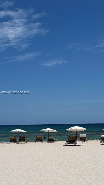 A sandy beach features several lounge chairs under white umbrellas overlooking the ocean — 5875 Collins Ave # 708, Miami Beach FL 33140, MIAMI BEACH, FL