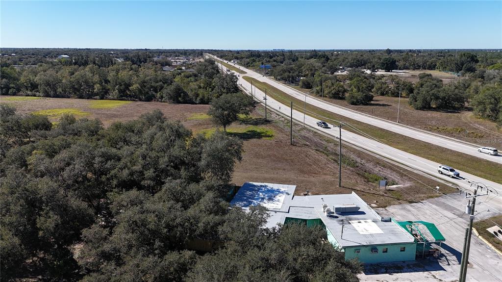 An aerial view shows a commercial building next to a highway surrounded by trees — 4224 DUNCAN ROAD, PUNTA GORDA, FL