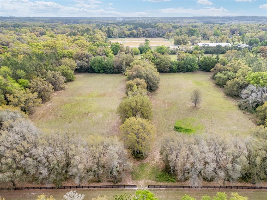 An aerial view shows two grassy pastures separated by a line of trees and fencing — 3595 NW 156TH DRIVE, NEWBERRY, FL