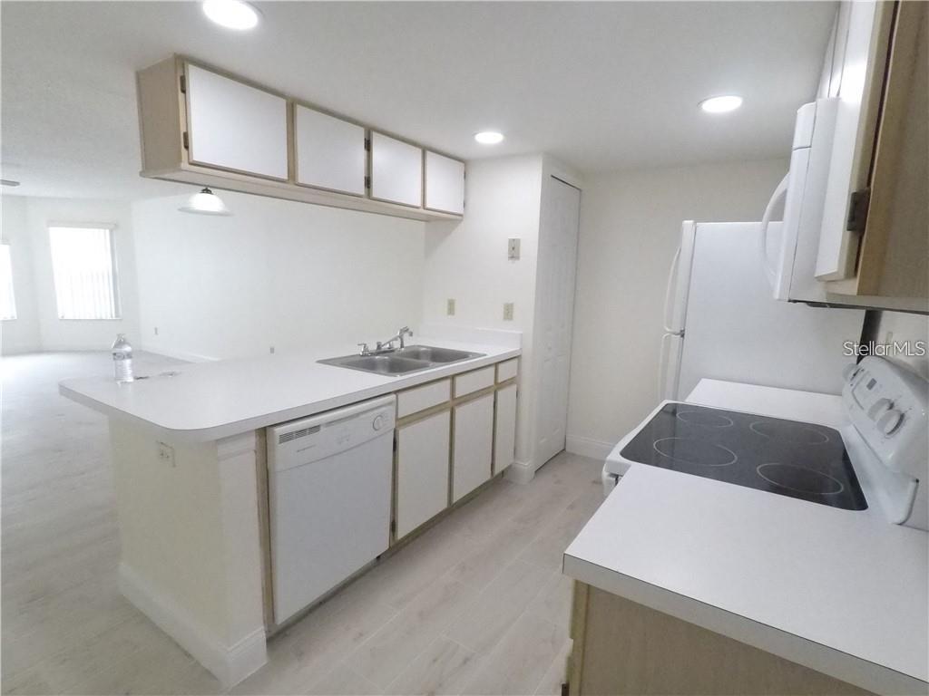 A kitchen features white cabinets, white countertops, a dishwasher, and a black electric stove — 2010 ROYAL BAY BOULEVARD UNIT 113, KISSIMMEE, FL