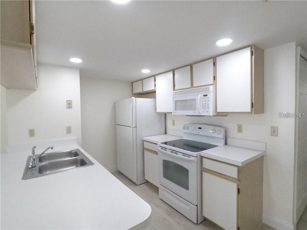 A kitchen features white cabinets, white appliances, and white countertops with a double sink — 2010 ROYAL BAY BOULEVARD UNIT 113, KISSIMMEE, FL
