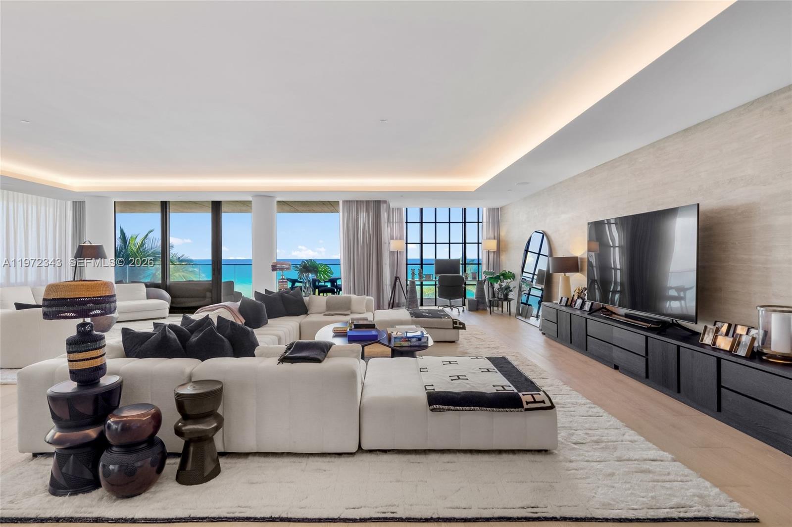 A spacious living room features a large white sectional, dark media console, and ocean views — 8955 NE Collins Ave # 301, Surfside FL 33154, SURFSIDE, FL