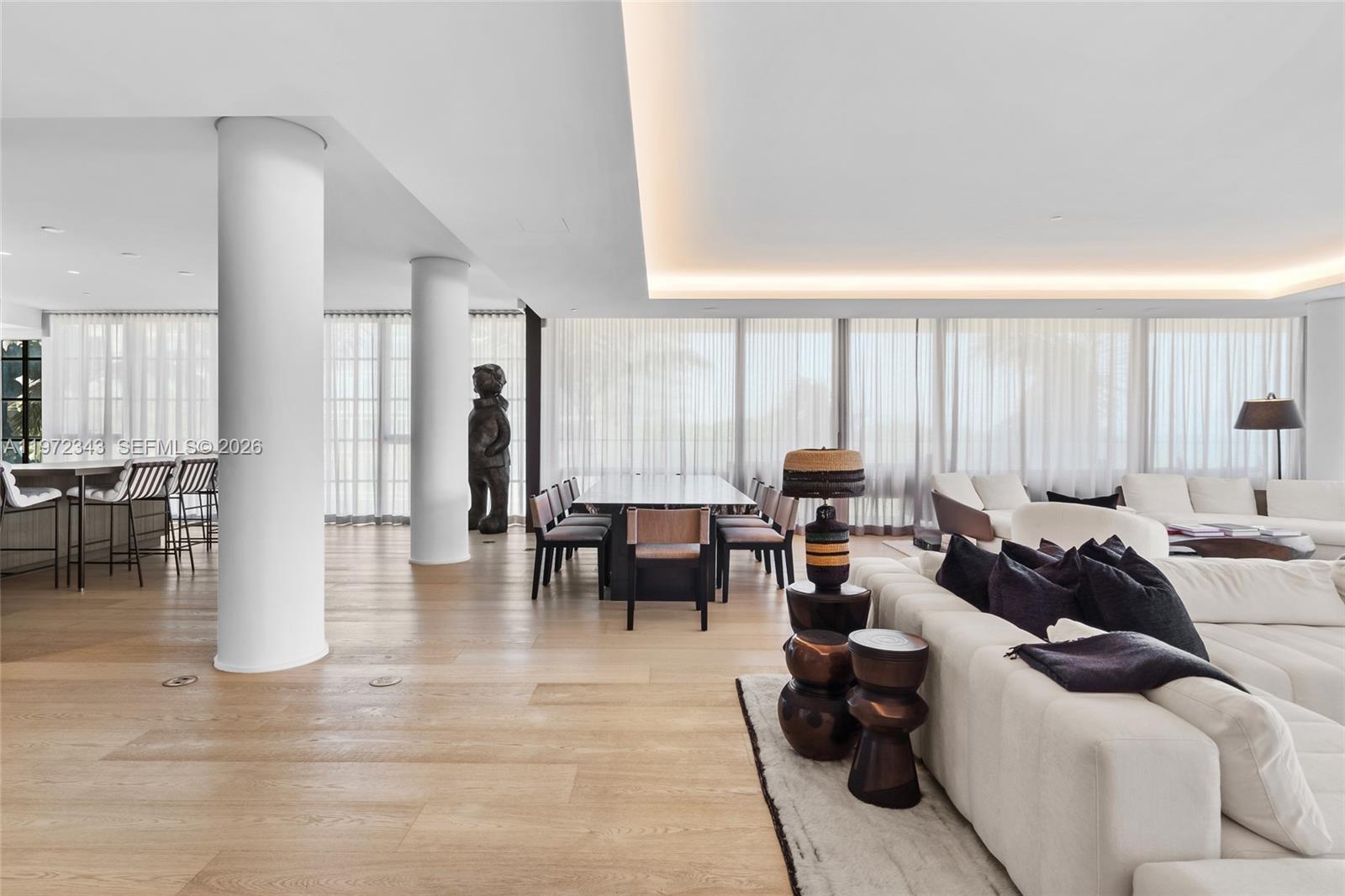 A spacious living and dining area features white columns, light wood floors, and modern furniture — 8955 NE Collins Ave # 301, Surfside FL 33154, SURFSIDE, FL