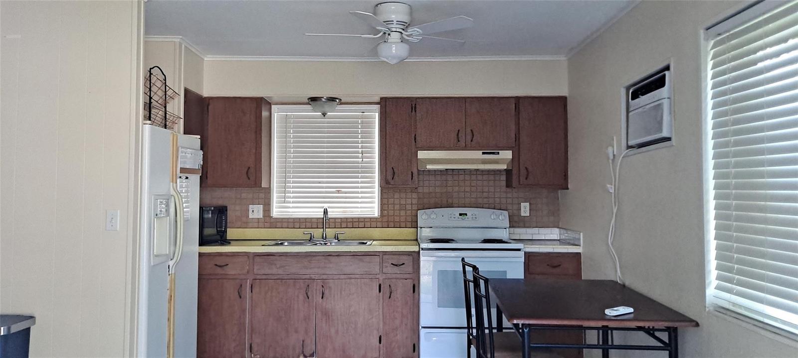 A kitchen features wood cabinets, a white stove, a sink, and a small dining table — 1118 Us Highway 441, Okeechobee FL 34974, OKEECHOBEE, FL