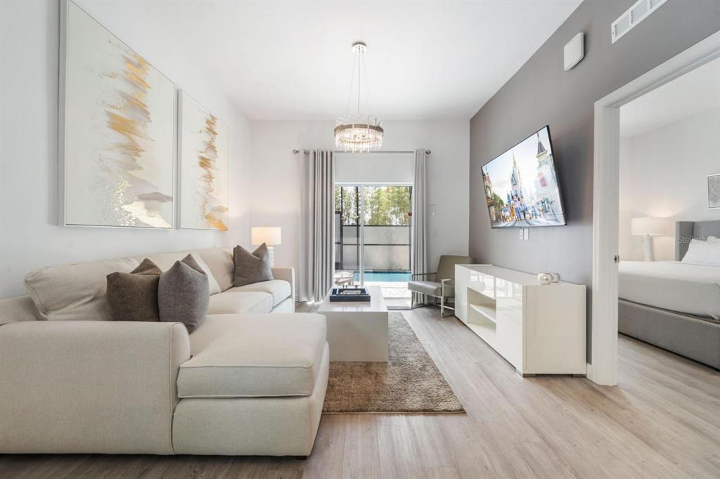 A living room features a sectional sofa, a white media console, and a sliding glass door — 384 FAMAGUSTA DRIVE, DAVENPORT, FL