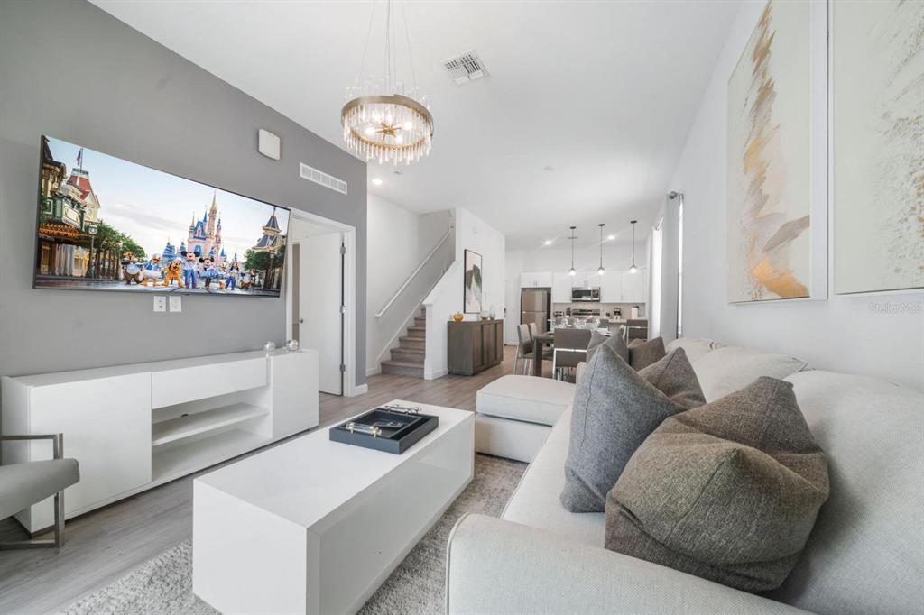 A modern living room with a large television, white media console, and gray sectional sofa — 384 FAMAGUSTA DRIVE, DAVENPORT, FL