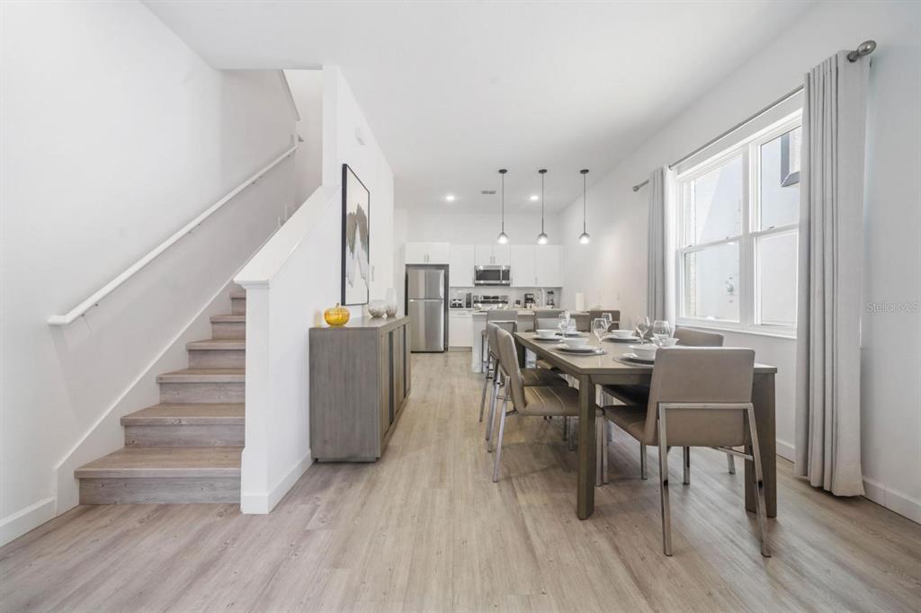 A dining area and kitchen with light wood flooring, a staircase, and modern white cabinetry — 384 FAMAGUSTA DRIVE, DAVENPORT, FL