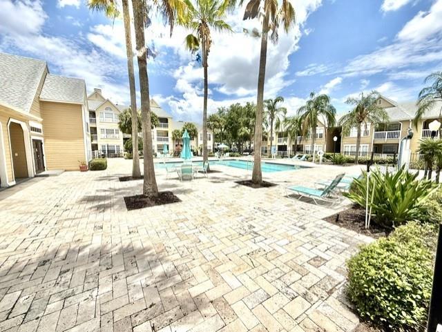 A paved pool deck features palm trees, lounge chairs, and multi-story apartment buildings — 1073 S HIAWASSEE ROAD UNIT 1015, ORLANDO, FL