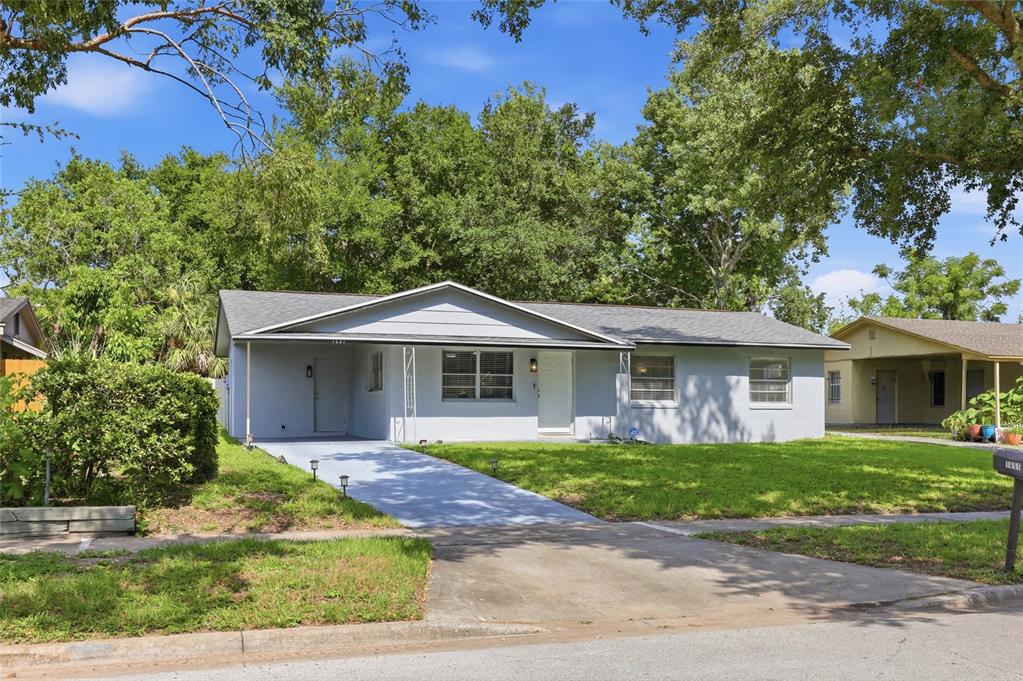 A light gray single-story house with a front carport, a concrete driveway, and mature trees — 1651 MESSINA AVENUE, ORLANDO, FL