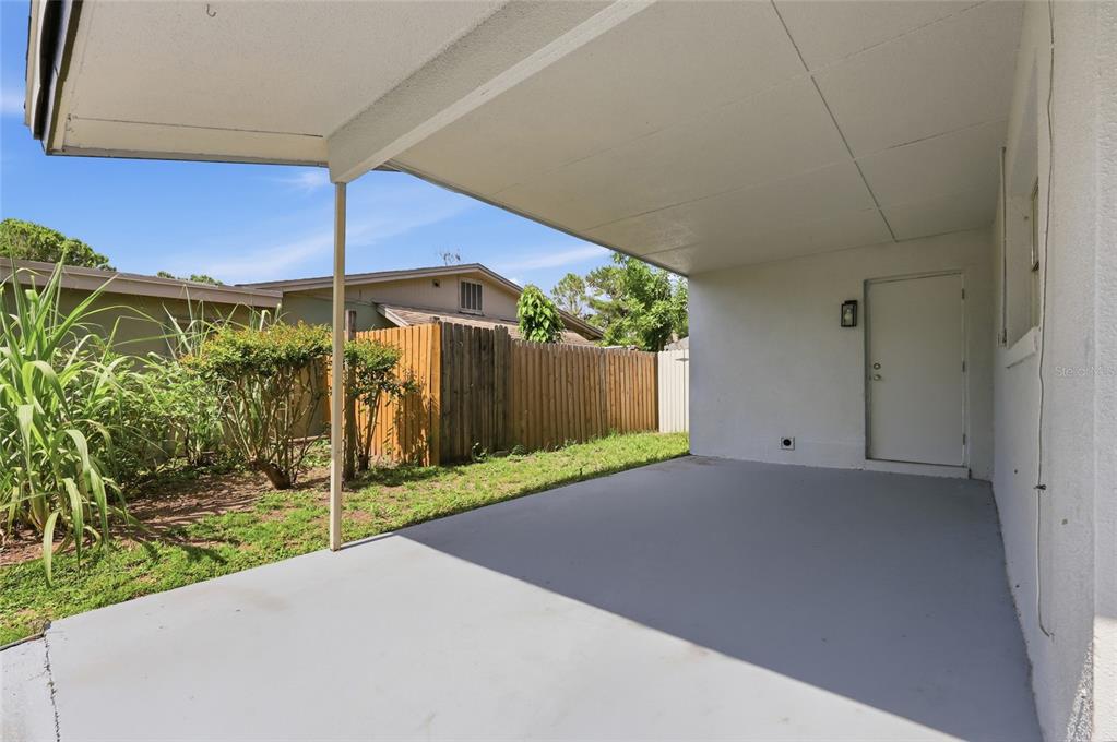 A covered concrete patio area sits adjacent to a white exterior wall and a door — 1651 MESSINA AVENUE, ORLANDO, FL