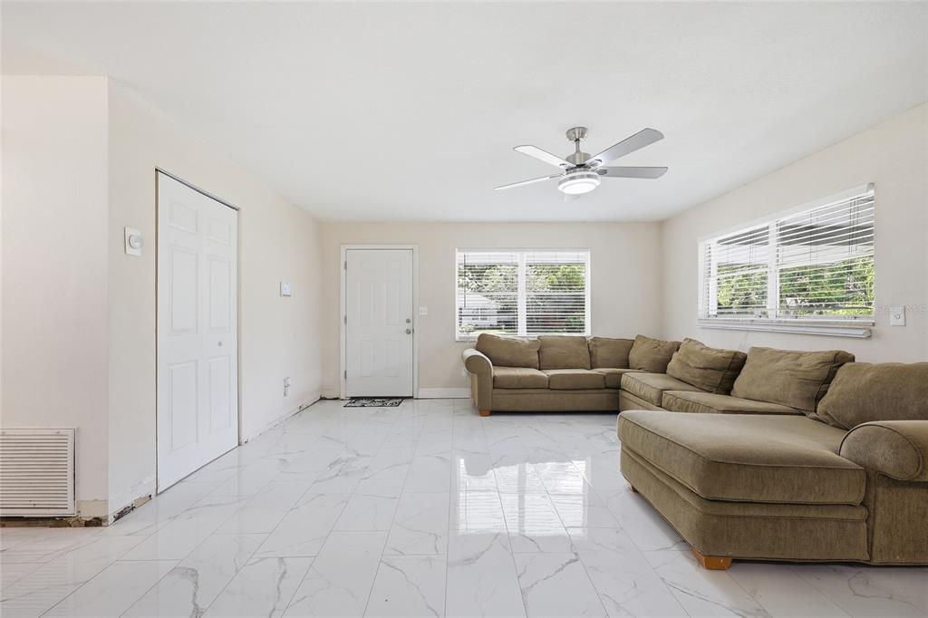 A living room with white marble-look tile flooring, a beige sectional sofa, and a ceiling fan — 1651 MESSINA AVENUE, ORLANDO, FL