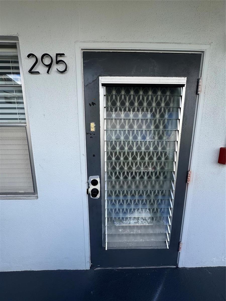 A dark-framed door with horizontal glass louvers is set into a light-colored exterior wall — 295 Newport T # 295, Deerfield Beach FL 33442, DEERFIELD BEACH, FL