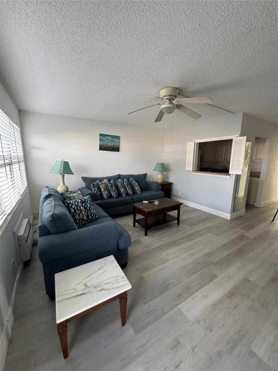 A living room features blue sofas, a coffee table, and light wood-look flooring — 295 Newport T # 295, Deerfield Beach FL 33442, DEERFIELD BEACH, FL
