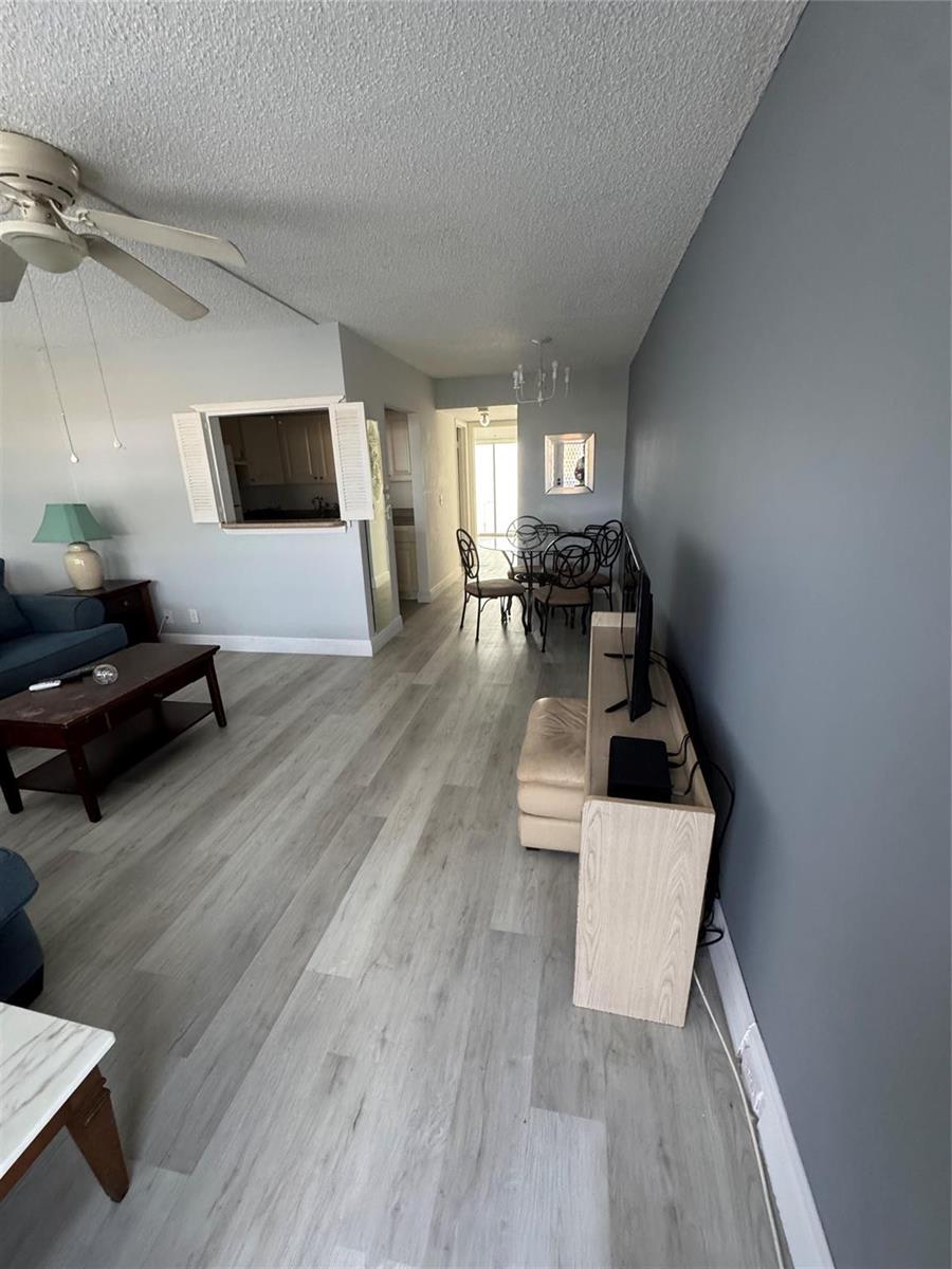 A living room and dining area feature light wood-look flooring and a dark accent wall — 295 Newport T # 295, Deerfield Beach FL 33442, DEERFIELD BEACH, FL