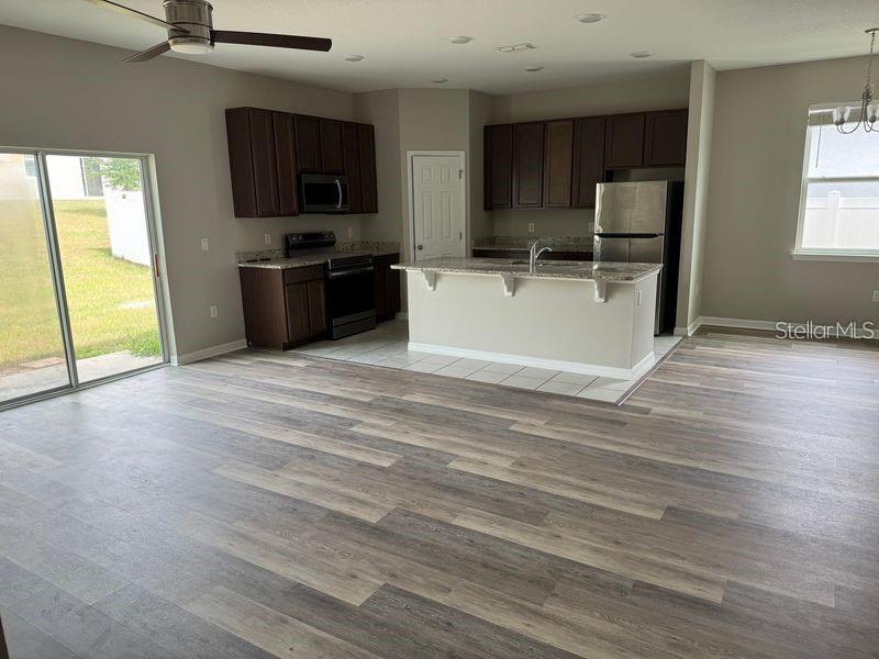 An open-concept kitchen features dark wood cabinets, stainless steel appliances, and a central island — 3345 CURLEW AVENUE, LEESBURG, FL