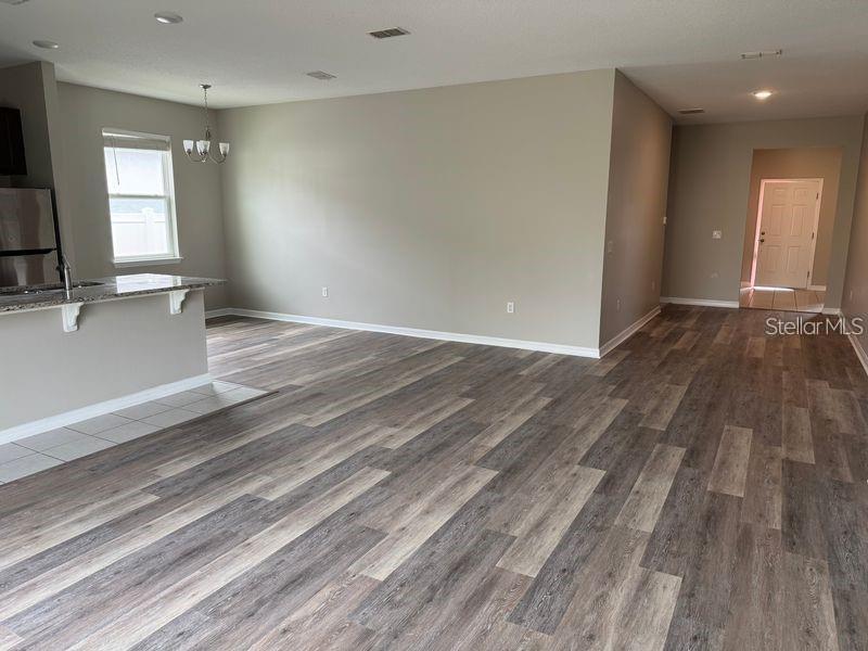 An open-concept living area features wood-look flooring, neutral walls, and a kitchen with granite countertops — 3345 CURLEW AVENUE, LEESBURG, FL