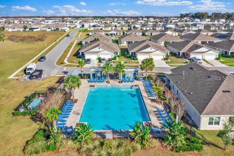 An aerial view shows a community swimming pool surrounded by lounge chairs and residential houses — 3345 CURLEW AVENUE, LEESBURG, FL