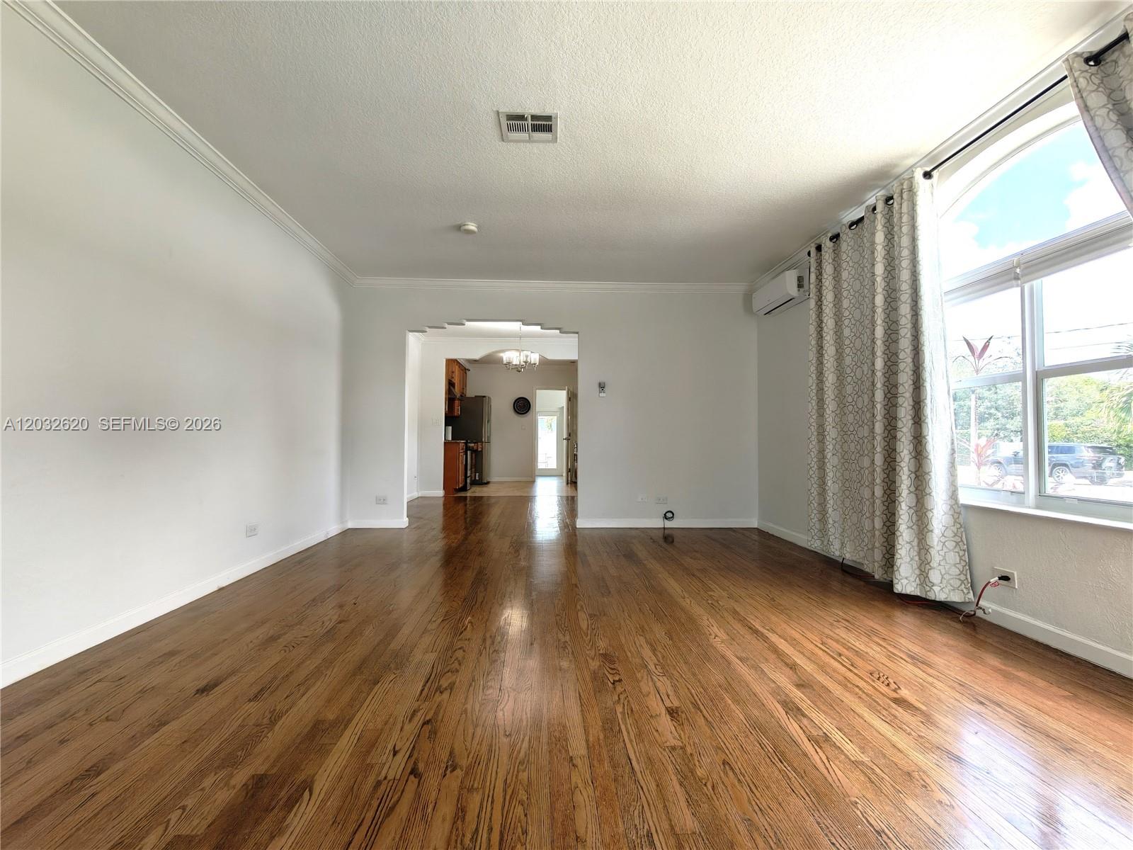 An empty living room with hardwood floors, white walls, and a window with curtains — 470 SW 25th Rd, Miami FL 33129, MIAMI, FL