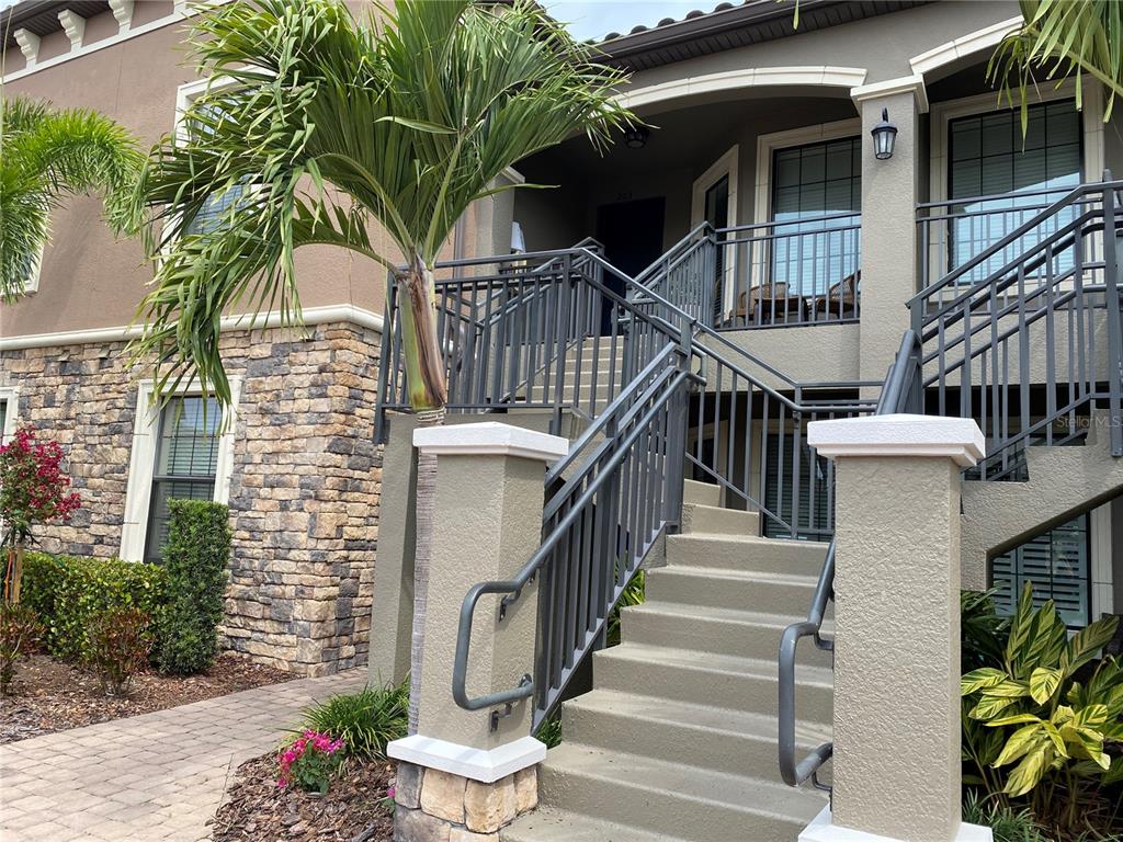 An exterior view shows a concrete staircase leading to a second-story balcony with metal railings — 13711 MESSINA LOOP UNIT 203, LAKEWOOD RANCH, FL