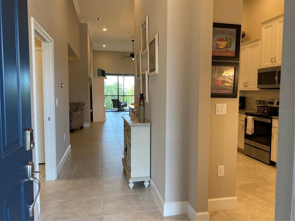 An entryway leads to a kitchen on the right and a living area with a balcony — 13711 MESSINA LOOP UNIT 203, LAKEWOOD RANCH, FL