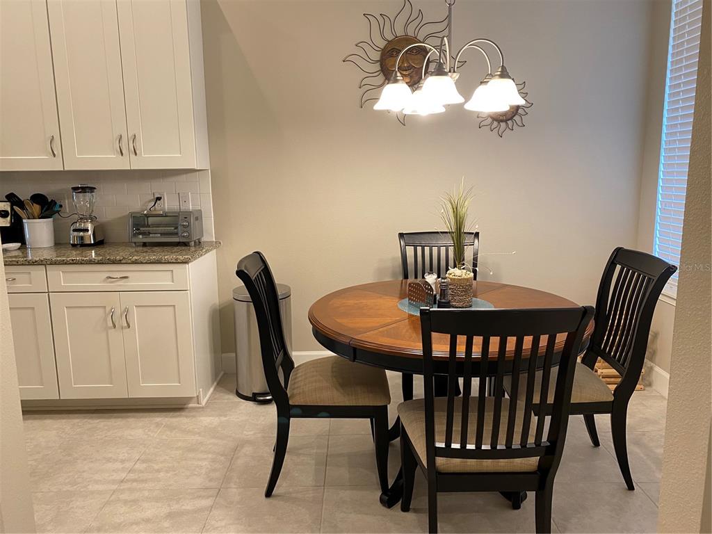 A kitchen dining area features white cabinets, a round wooden table, and four chairs — 13711 MESSINA LOOP UNIT 203, LAKEWOOD RANCH, FL