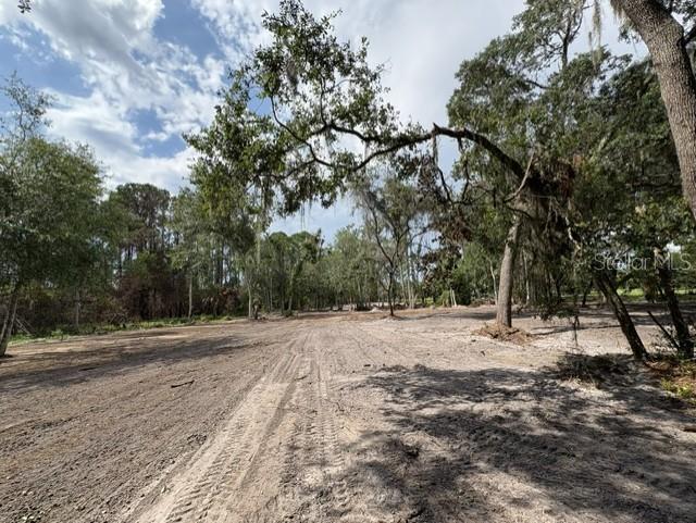A cleared, sandy lot with tire tracks is surrounded by mature trees under a cloudy sky — COUNTY ROAD 309, CRESCENT CITY, FL