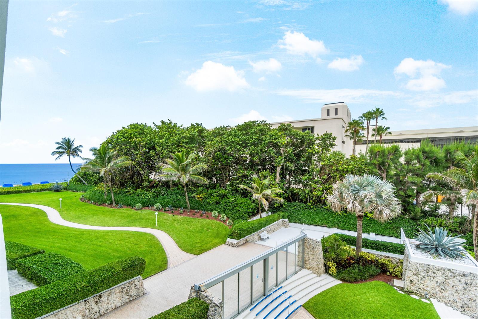 An elevated view of a landscaped lawn, palm trees, and a walkway near the ocean — 2780 S Ocean Boulevard # 306, Palm Beach FL 33480, PALM BEACH, FL