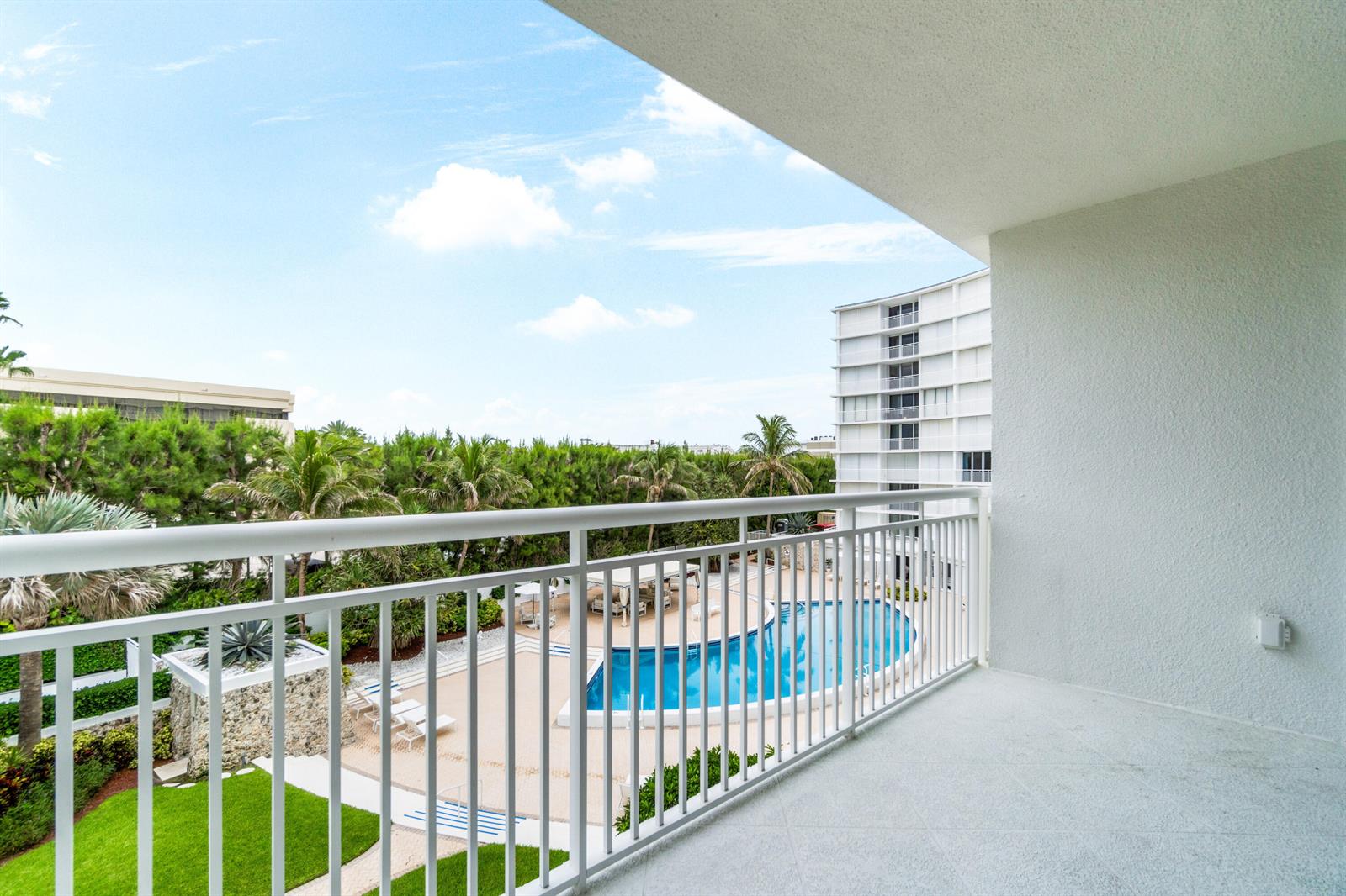 A white balcony overlooks a swimming pool, palm trees, and a multi-story building — 2780 S Ocean Boulevard # 306, Palm Beach FL 33480, PALM BEACH, FL