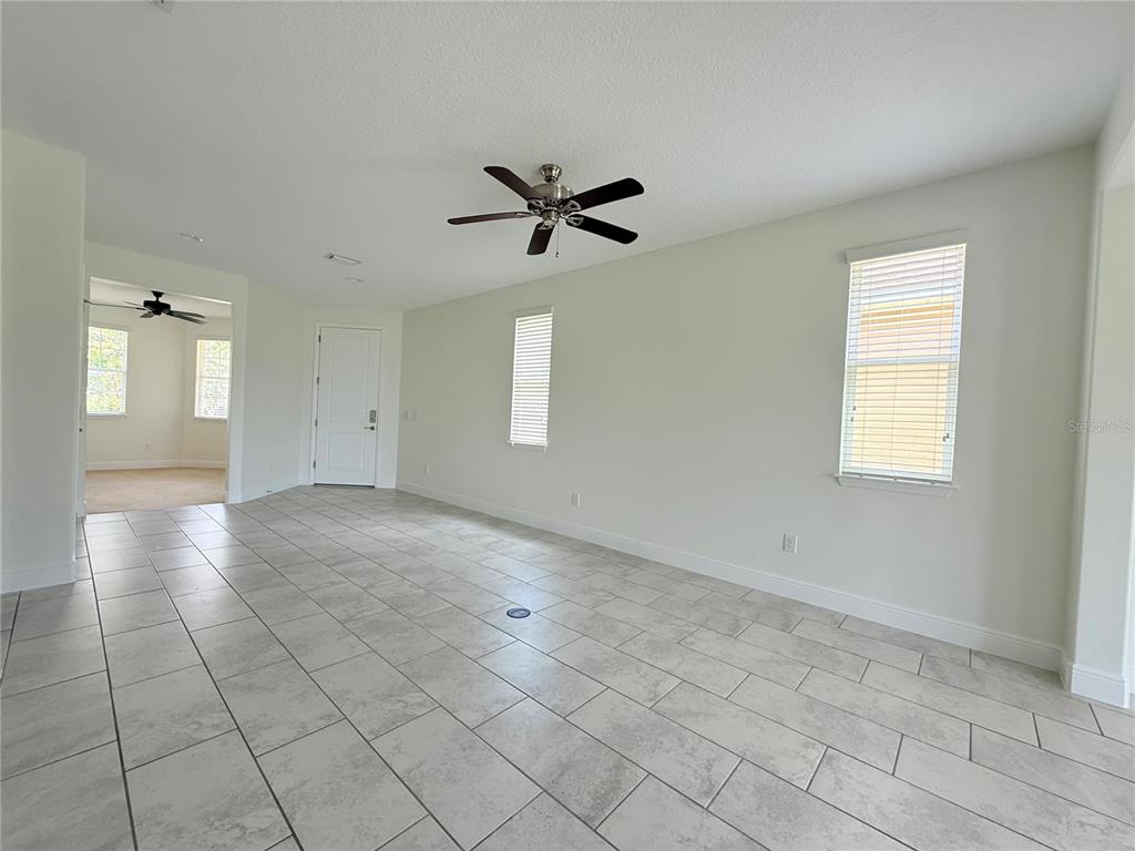 An empty room with light-colored tile flooring, white walls, two windows, and a ceiling fan — 5057 NW 35TH PLACE, OCALA, FL