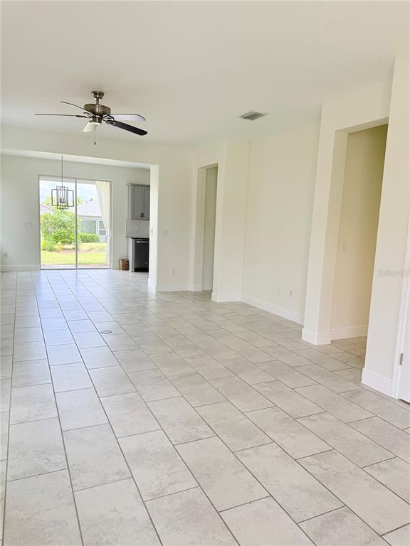 An open-concept living area features light-colored tile flooring, a ceiling fan, and sliding glass doors — 5057 NW 35TH PLACE, OCALA, FL