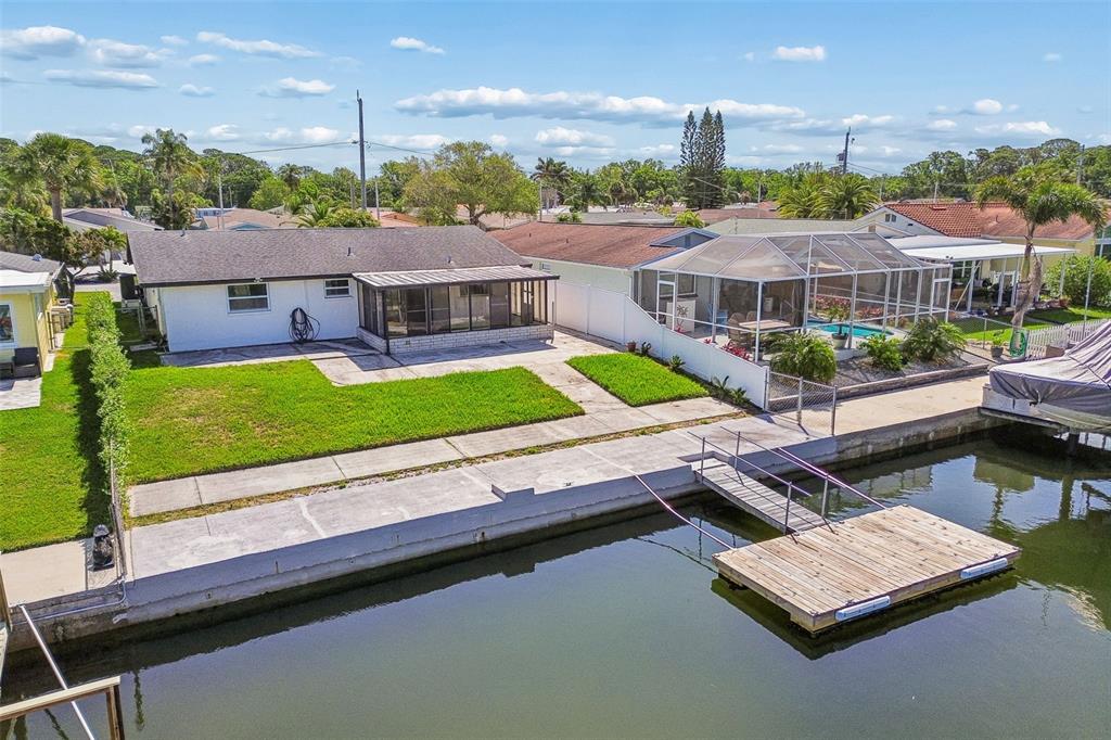 An aerial view of a waterfront house with a lawn, patio, and private wooden dock — 4931 POMPANO DRIVE, NEW PORT RICHEY, FL